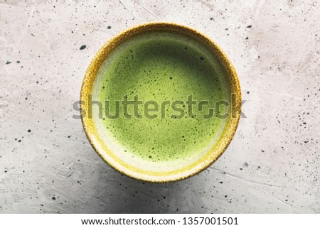 Top view of green tea matcha in a bowl on concrete surface. It is a rich source of antioxidants and polyphenols. When preparing, the powder is partially dissolved in hot water