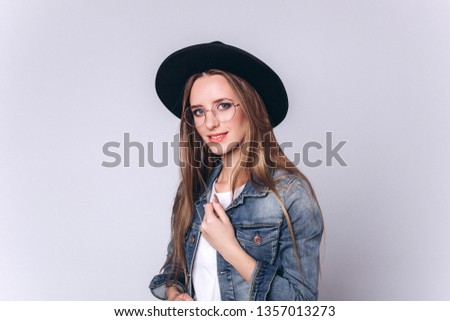 Beautiful caucasian young cheerful hipster stylish girl model in black hat isolated on grey background. Fashion, professional model, style concept 