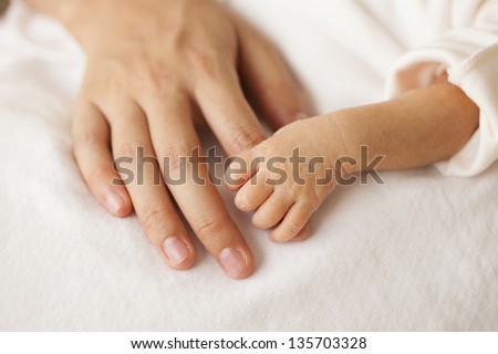Baby hands and the hands of his mother. Royalty-Free Stock Photo #135703328