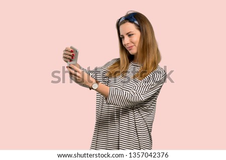 Young woman with headscarf making a selfie over isolated pink background