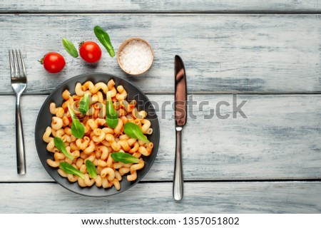 Delicious Italian pasta with tomato sauce, on a plate on a wooden table. View from above