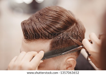 Close-up, master hairdresser does hairstyle with scissors comb. Concept Barbershop. Royalty-Free Stock Photo #1357063652