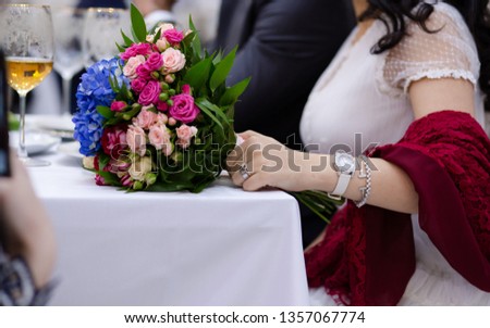 Bride holding her wedding flowers on the table. A glass of wine. Royalty-Free Stock Photo #1357067774
