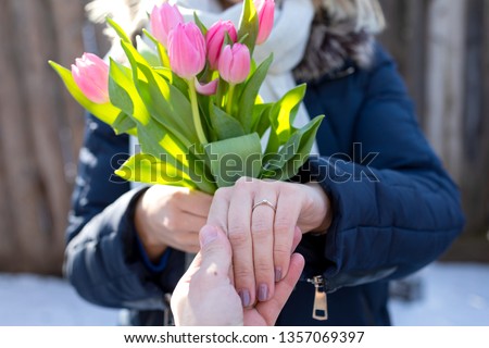 Close up picture of engagement ring on female hand, bouquet of pink tulips outdoor, winter- proposal, love, marriage