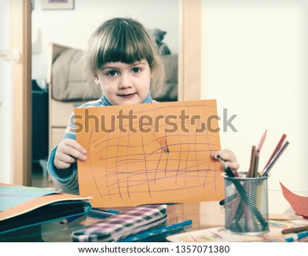 serious child with drawed paper in home interior