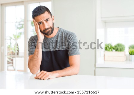 Handsome hispanic man wearing casual t-shirt at home thinking looking tired and bored with depression problems with crossed arms.