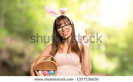 Young woman wearing bunny ears for Easter holidays showing an ok sign with fingers at outdoors