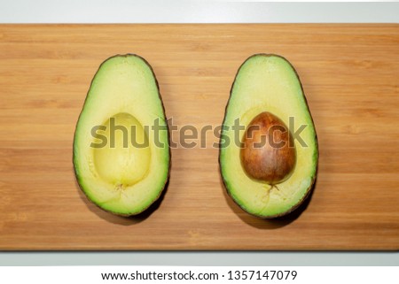 Avocado cut half on a bamboo cutting board