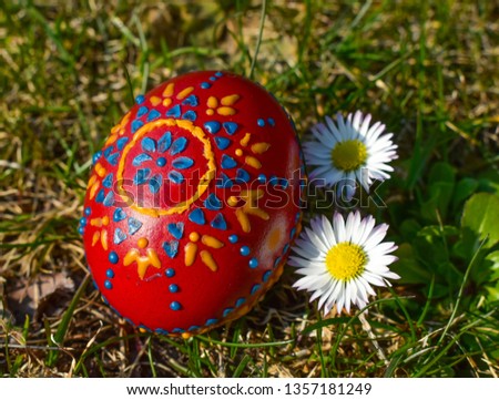 Decorated easter eggs in the grass with daisies.