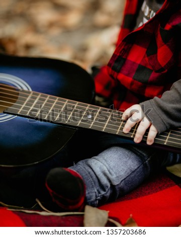 Baby boy holding the neck of the guitar. Guitarist kid. Royalty-Free Stock Photo #1357203686