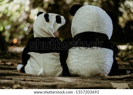 From behind of baby boy wearing bear costume sitting near to teddy bear Royalty-Free Stock Photo #1357203692