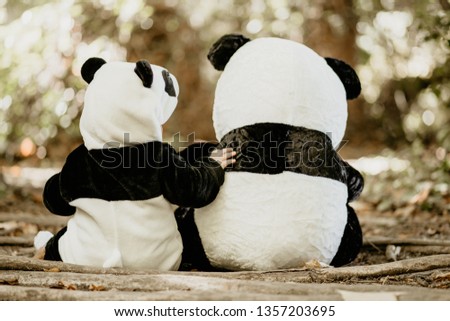 From behind of baby boy wearing bear costume sitting near to teddy bear Royalty-Free Stock Photo #1357203695