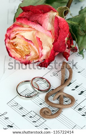 Treble clef, roses and wedding rings on musical background