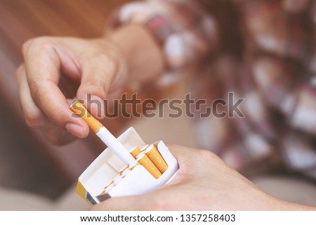 close up man hand holding peel it off cigarette pack prepare smoking a cigarette. Packing line up. photo filters Natural light. Royalty-Free Stock Photo #1357258403