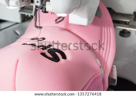 Embroidered pink cap on hoop of embroidery machine close up image