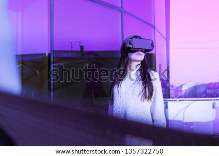 A young girl with a headset on the face meets new technologies. Woman using virtual reality headset on winter's street.