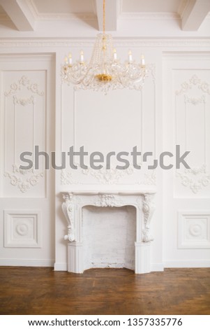 Royal interior in white colors. Elegant white fireplace in beautiful white room. White hall with fireplace