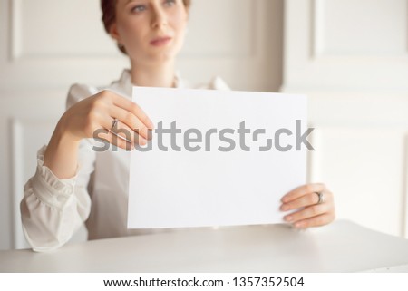 Woman holding white business card on white wall background