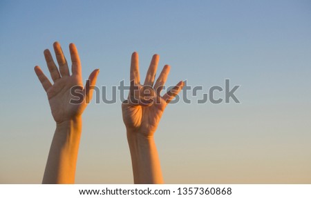 Hands showing number nine gesture symbol on blue summer sky nature background. Gesturing number nine (9) in sign language. Ninth, counting down nine concept. Nine fingers up. Space for ad text.