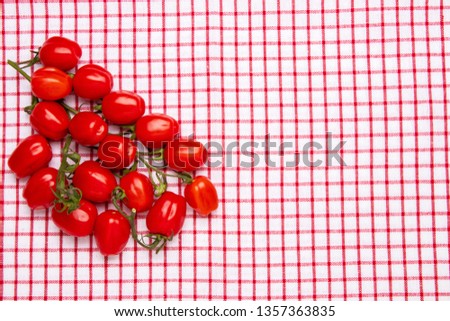 Healthy food background. Top view of fresh red cherry tomatoes on a red checkered napkin or towel. Place for your design. Concept health.