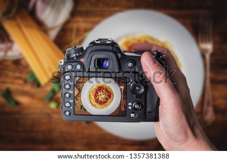 Man taking photo of Italian spaghetti bolognese with tomato sauce and meat