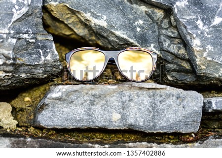 unisex sun glasses with mirrored lenses on stone background in nature