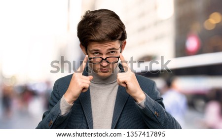 Teenager man with turtleneck with glasses and surprised at outdoors