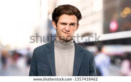 Teenager man with turtleneck with confuse face expression while bites lip at outdoors