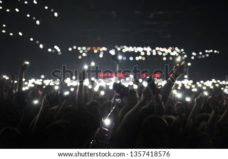 Concert crowd background. Group of happy music fans put mobile phone lights up on rock concert. Cheerful young people partying on electronic musical festival in night club. Wallpaper design template