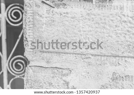 A close-up of a fragment of an old rural door. Stone fence and metal door with ornaments. Shallow depth of focus, texture, background. Black and White potography.
