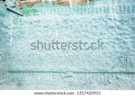 A close-up of a fragment of an old rural door. Stone fence painted in green and metal door with ornaments. Shallow depth of focus, texture, background.