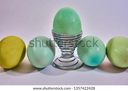 5 blue eggs with one in an egg cup on a white background