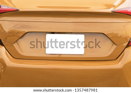 Horizontal shot of a blank white license plate on a gold car with copy space.