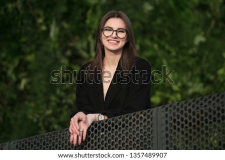 Beautiful young adult smiling woman with glasses smiling outdoors in the park