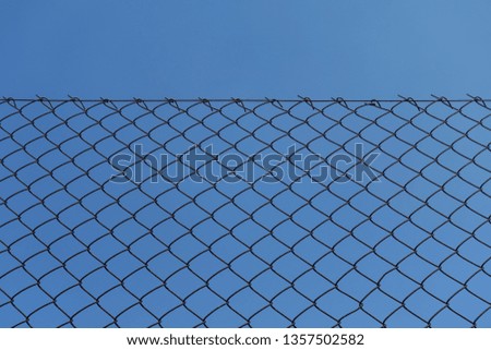 Rusty chain link fence and blue sky background texture.