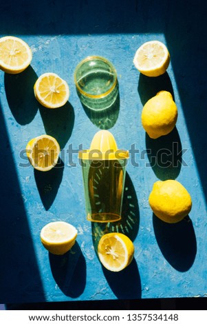Lemon juice  squeezer colored yellow with lemon fruit whole and cut in half,, top view with strong directional light forming hars shadow, summertime fresh concept