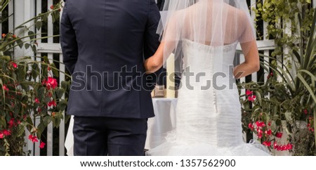 Wedding back view; Man in navy suit; Woman in white wedding dress; outdoors ceremony; sentimental colors