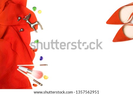 Flat lay female fashion outfit set: red cloth, heels, makeup, brushes, earrings, silver deer on white background. Christmas, Happy New Year, Valentine's day Party concept. Top view, copy space.
