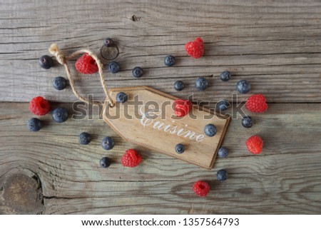Blueberries and raspberrieswith a coisine decorative wooden plate close-up on an old wood background. Vegan food. Healthy eating concept.