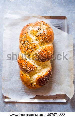  Challah bread ready out of oven, warm over a metal tray with   cooking paper, top view, natural light, hebraism traditional bread.