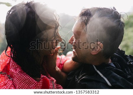 Close-up portrait of loving couple kissing on nature background. Brunette man and woman looking at each other with love.