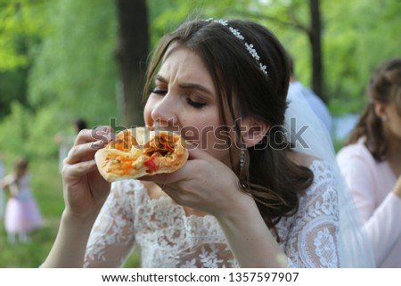 Wedding photo bride eats pizza outdoors in the forest. Royalty-Free Stock Photo #1357597907