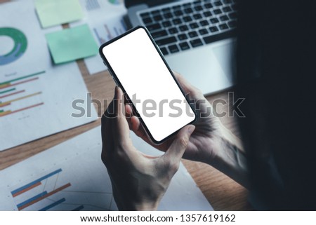 mockup image of cell phone white blank screen for text.Businessman at workplace Think business investment plan.Contact Investor using mobile,computer.make note appointment information in the notebook