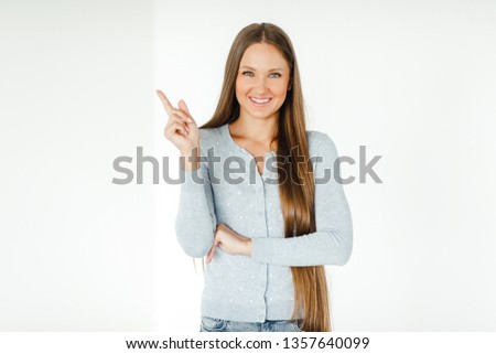 Young happy woman pointing her finger on the empty copyspace isolated over white background