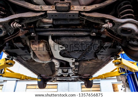 View of car undercarriage when lifted on hydraulic lift in a workshop during inspection Royalty-Free Stock Photo #1357656875