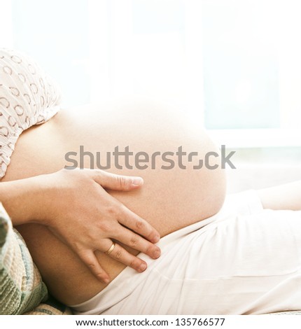 Photo of pregnant woman lying  on window background