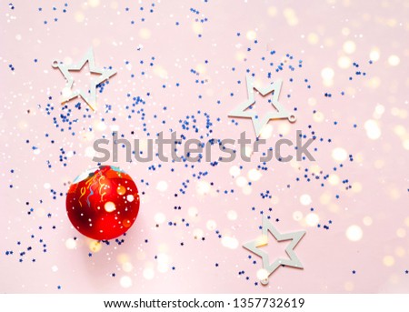 Christmas red ball on pink background with blur effect.  Festive backdrop for package and projects. Close up, copy space.