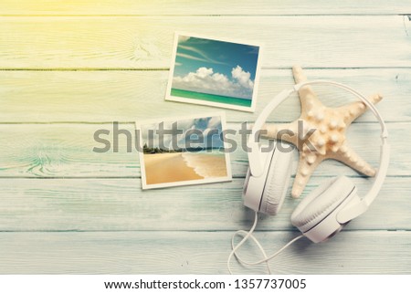 Travel vacation and music concept with headphones, starfish and photos on wooden backdrop. Top view with copy space. Flat lay. All photos taken by me. Sunny toned