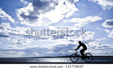 silhouette of cyclist in motion on the background of a beautiful blue sky