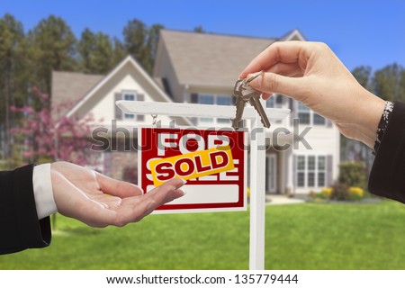 Real Estate Agent Handing Over the House Keys in Front of a Beautiful New Home.